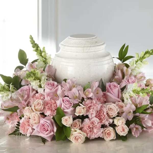 Pink roses and carnations arranged around a white urn