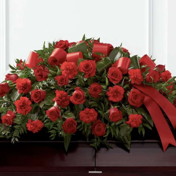 Red roses and carnations arranged with red ribbon on a casket