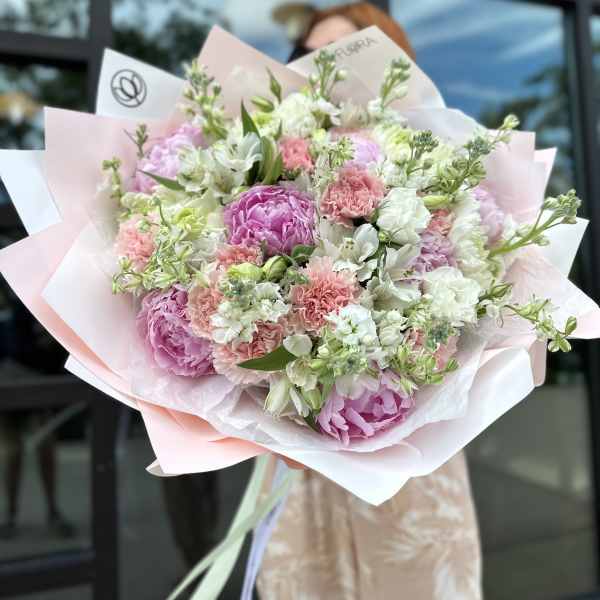 Large bouquet of pink and white flowers wrapped in pastel paper