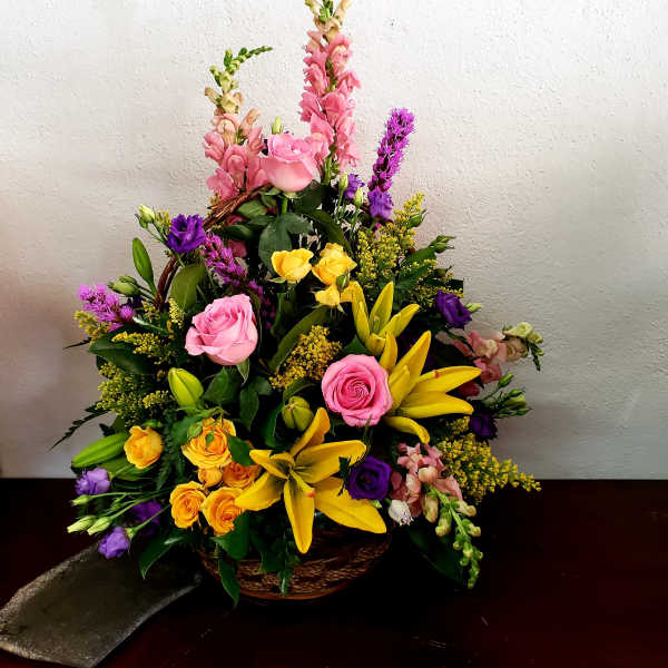 Mixed bouquet of pink, yellow, and purple flowers in a basket