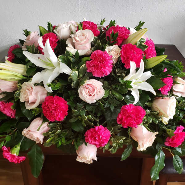 Large floral casket spray with pink roses, white lilies, and hot pink carnations