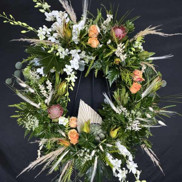 Large floral wreath with white orchids, peach roses, and pink protea