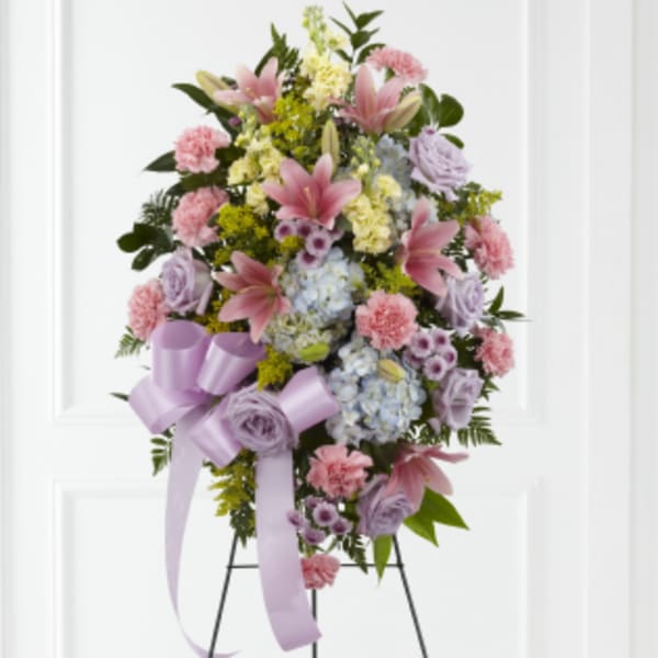 Standing floral spray with pink lilies, carnations, and lavender roses on an easel