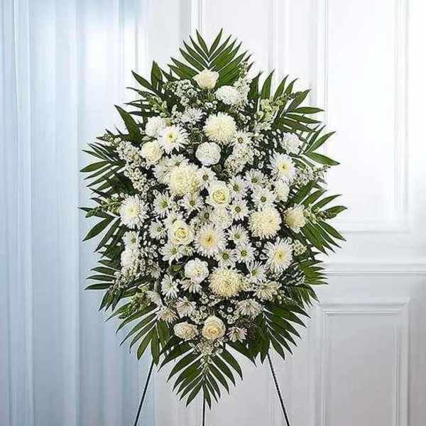 White funeral spray on an easel with palm fronds