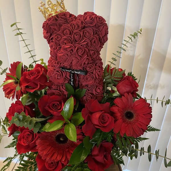 Red rose teddy bear with a gold crown, surrounded by red roses and gerbera daisies