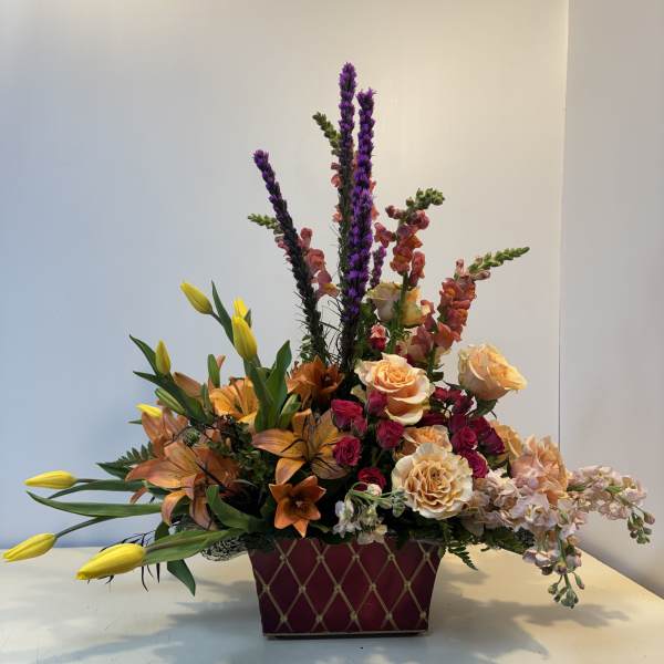 Mixed bouquet in a burgundy rectangular container with roses and lilies