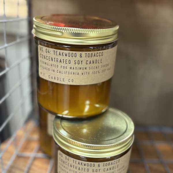 Two amber jar candles with gold lids stacked on a wire rack