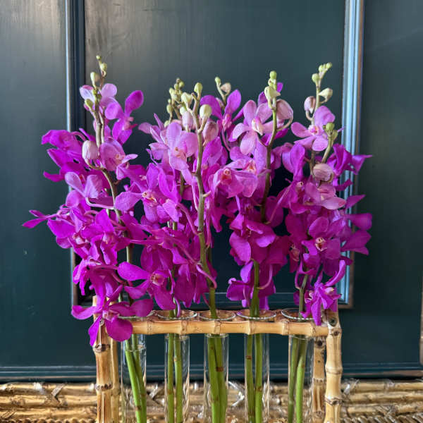 Pink orchids arranged in glass tubes inside a bamboo holder