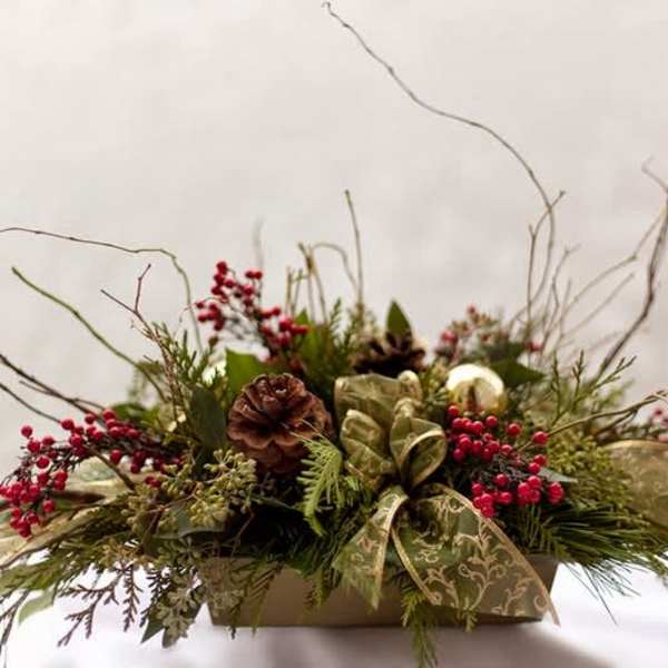 Holiday centerpiece with pinecones, red berries, and a patterned ribbon in a low container