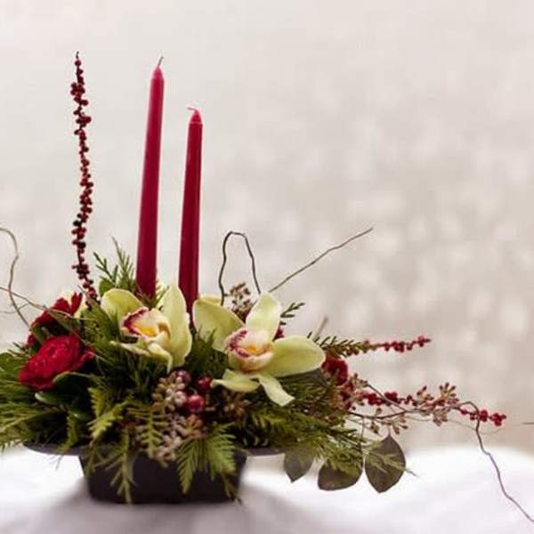Red candle centerpiece with orchids and greenery in a low container