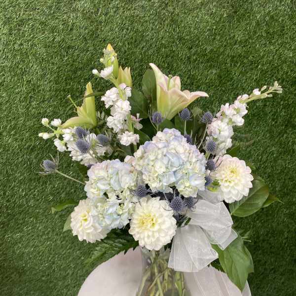 Bouquet of white and pale pink flowers in a glass vase with a sheer ribbon