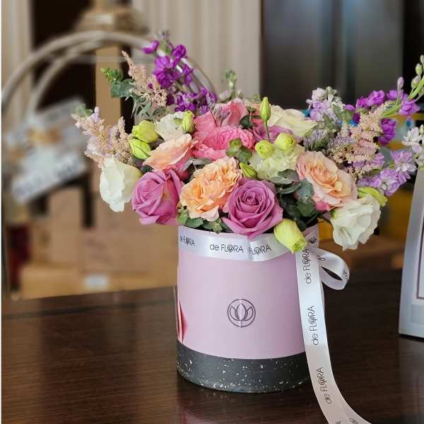 Pink and peach roses in a round gift box with a ribbon