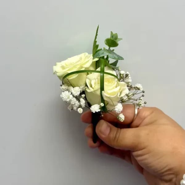 Small white rose boutonniere with baby's breath and greenery