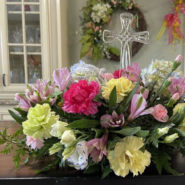 Colorful floral casket spray with a clear glass cross centerpiece