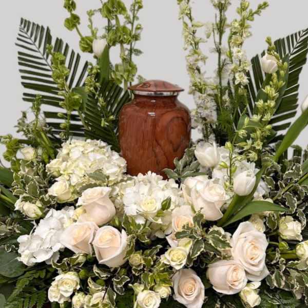White roses and tulips arranged around a wooden urn