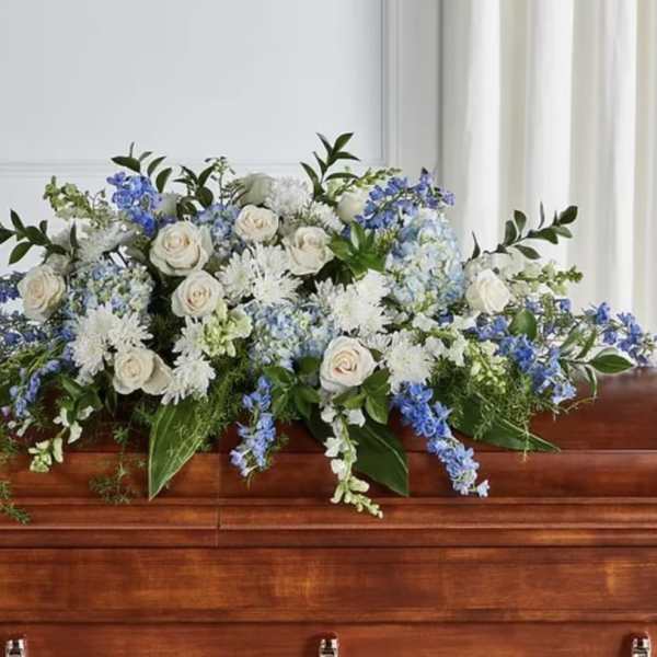White and blue floral arrangement on a casket