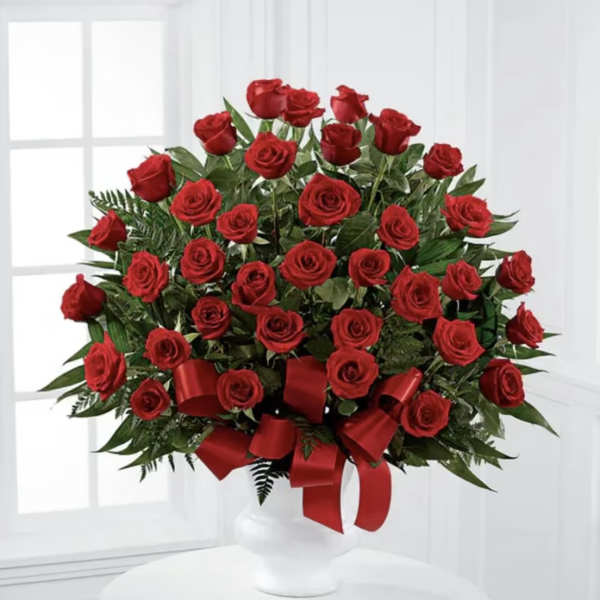 Red rose arrangement in a white vase with a red ribbon