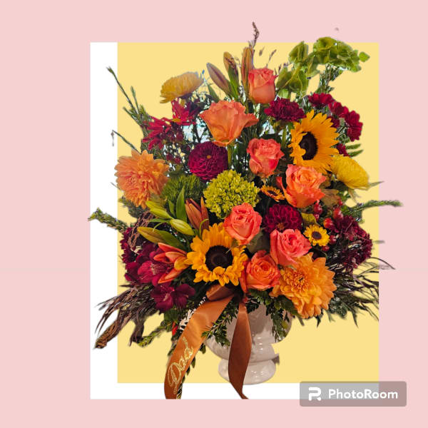 Mixed bouquet of orange, yellow, and burgundy flowers in a white vase