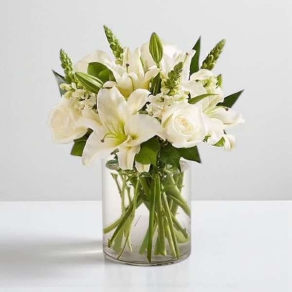 White lilies and roses arranged in a clear glass vase