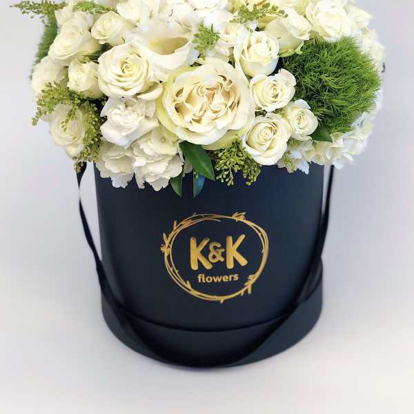 White rose arrangement in a black hatbox with gold logo