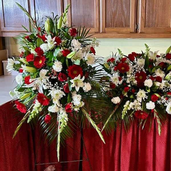 Two large red and white floral sprays on a table in a room