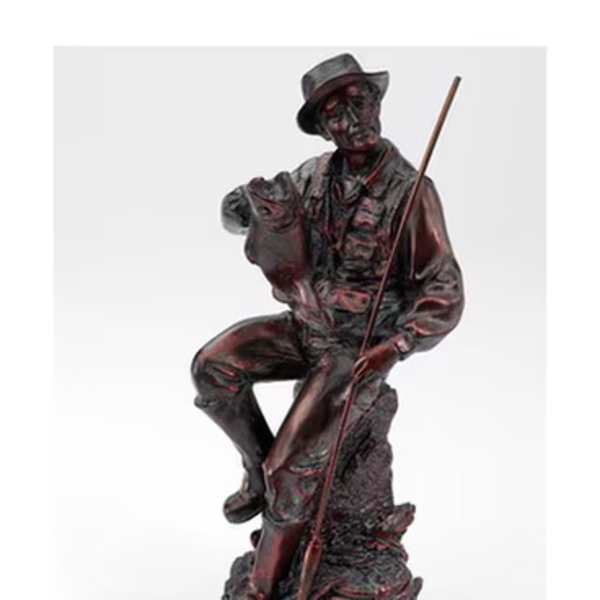 Dark figurine of a seated man holding a fishing rod