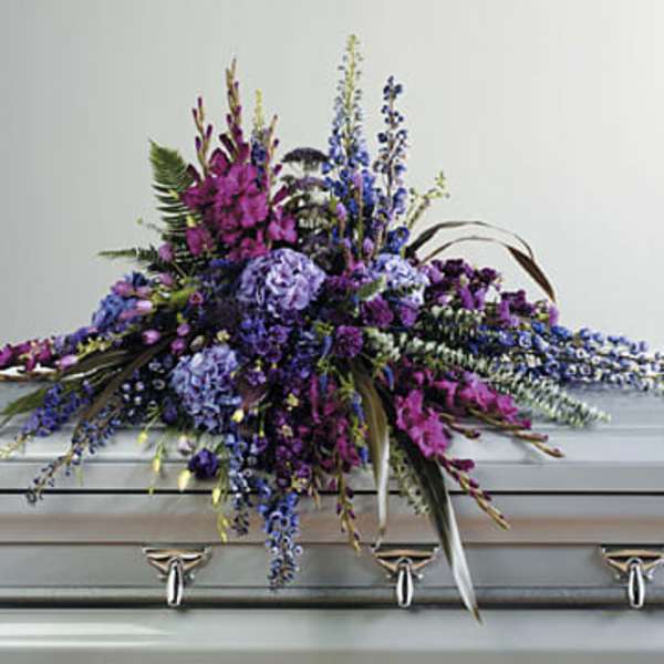 Purple and blue floral casket spray on a silver casket
