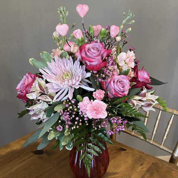 Pink and lavender floral arrangement in a red vase