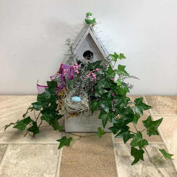 Birdhouse planter with ivy, pink accents, and a nest decoration