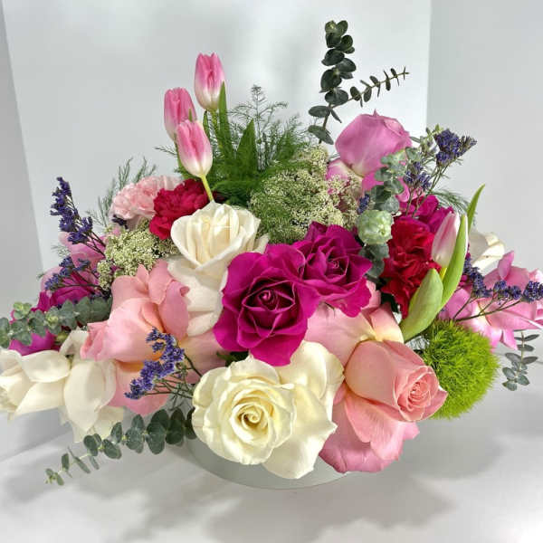 Mixed bouquet of pink, white, and magenta roses with tulips in a low vase