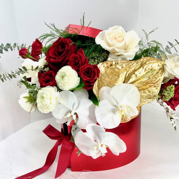 Bouquet of red and white roses with white orchids in a red box
