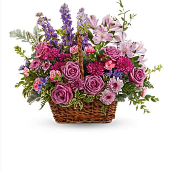 Basket arrangement of purple and pink flowers with a wicker handle