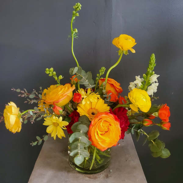 Yellow and orange mixed flower arrangement in a glass vase