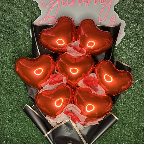 Bouquet of red heart-shaped balloons wrapped in black paper with a red ribbon