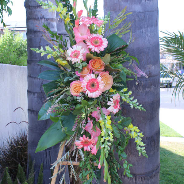 Tall floral spray with pink gerbera daisies and peach roses on a stand