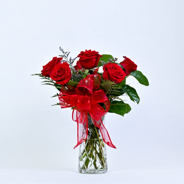 Red roses in a clear glass vase with a red ribbon bow