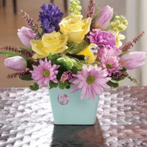 Mixed bouquet in a light blue square vase with yellow roses and pink tulips
