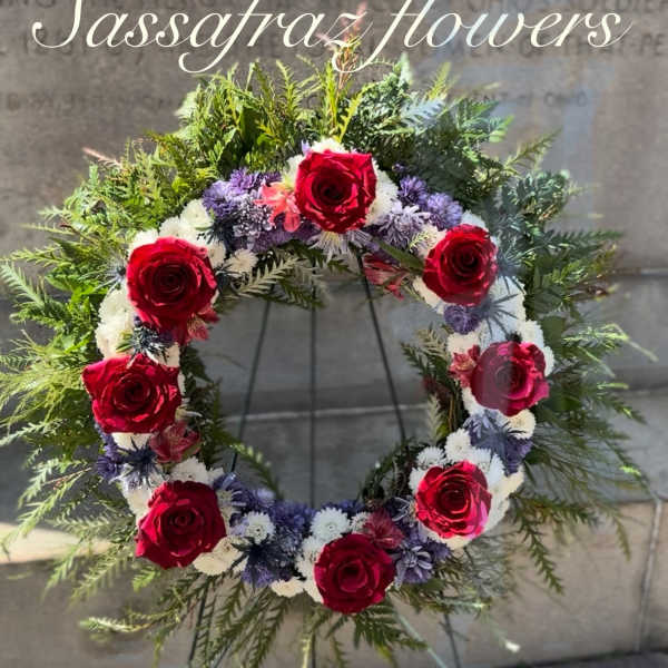Circular floral wreath with red roses and purple-white flowers