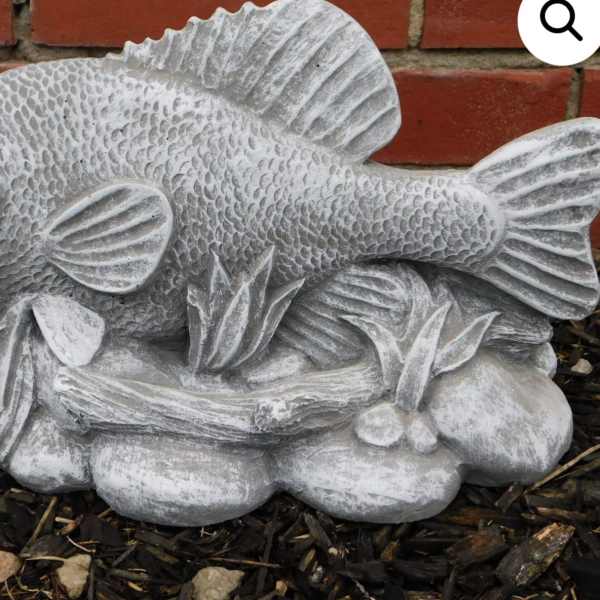 Gray fish garden statue on a brick and mulch background