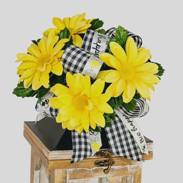Yellow daisy bouquet on a rustic lantern with a candle inside