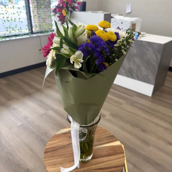 Mixed bouquet of white, purple, yellow, and pink flowers in a glass vase