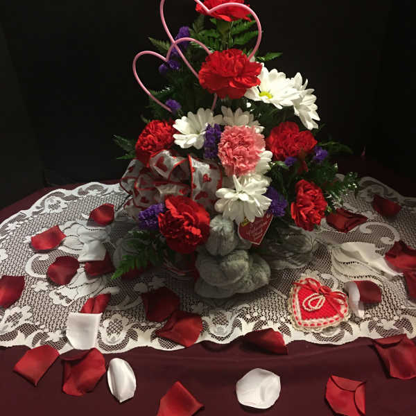 Heart-shaped floral arrangement with red, white, and pink flowers