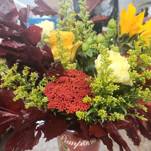 Autumn bouquet with yellow and cream flowers in a pumpkin vase