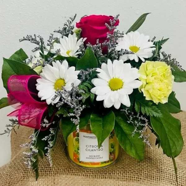 Bouquet of daisies and roses arranged around a scented candle jar