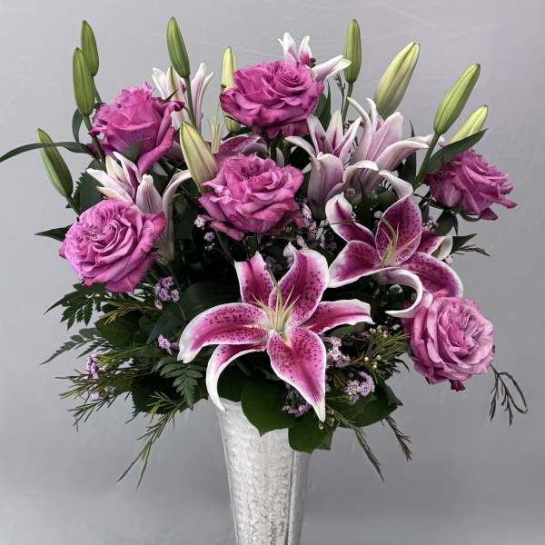 Pink roses and lilies arranged in a silver vase