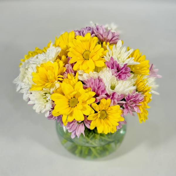Bouquet of yellow, white, and pink daisies in a glass vase