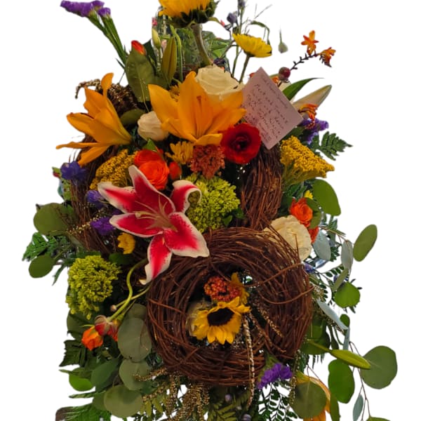 Tall floral standing arrangement with sunflowers, lilies, and roses