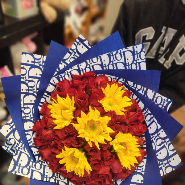 Bouquet of red roses with yellow sunflowers wrapped in blue paper