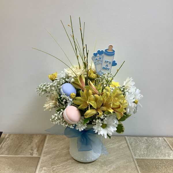 Bouquet of yellow and white flowers in a polka-dot vase with a baby boy topper