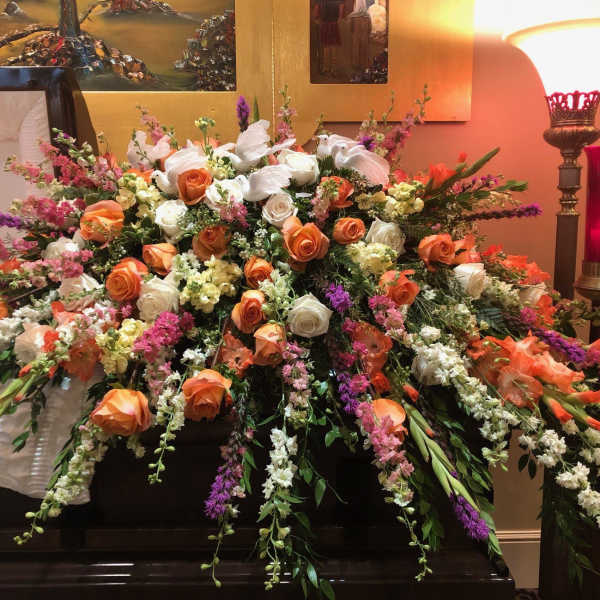 Large casket spray of orange and white roses with pink and purple flowers